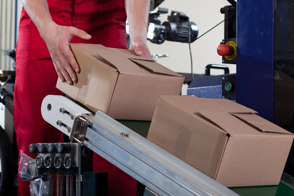 Close-up of worker putting a box on conveyor belt for shipping