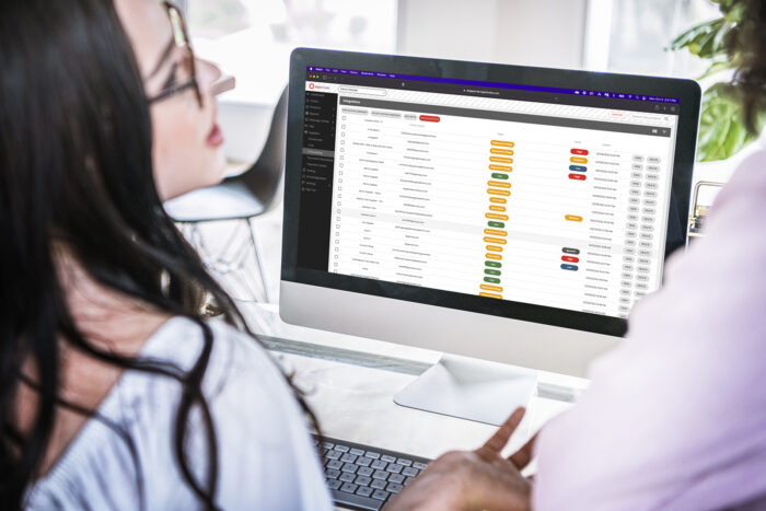 Two women viewing Logicbroker portal on computer screen, on-demand onboarding interface